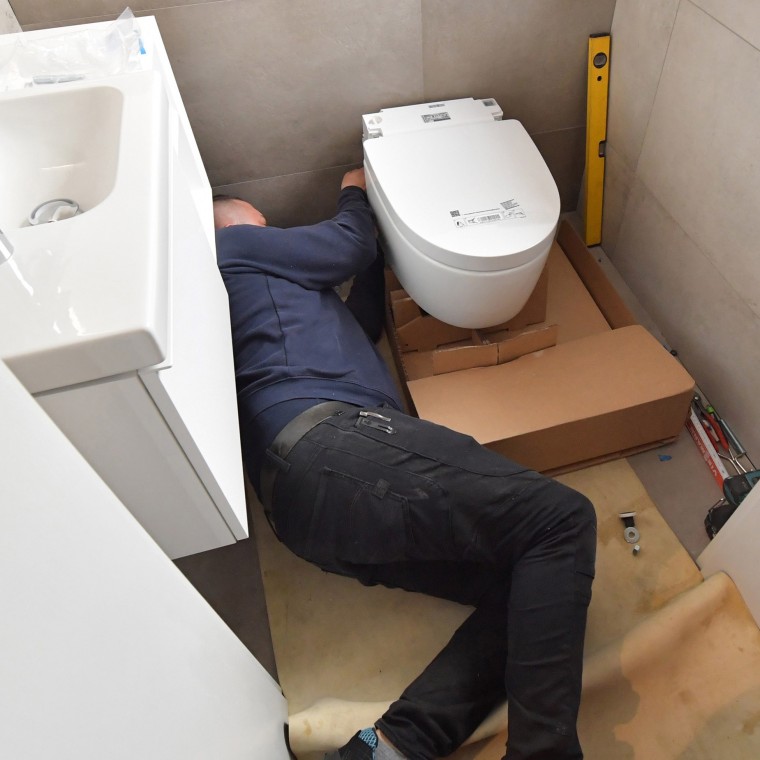 Installateur montiert das Geberit AquaClean WC im Gästebad Installateur montiert das Geberit AquaClean WC im Gästebad