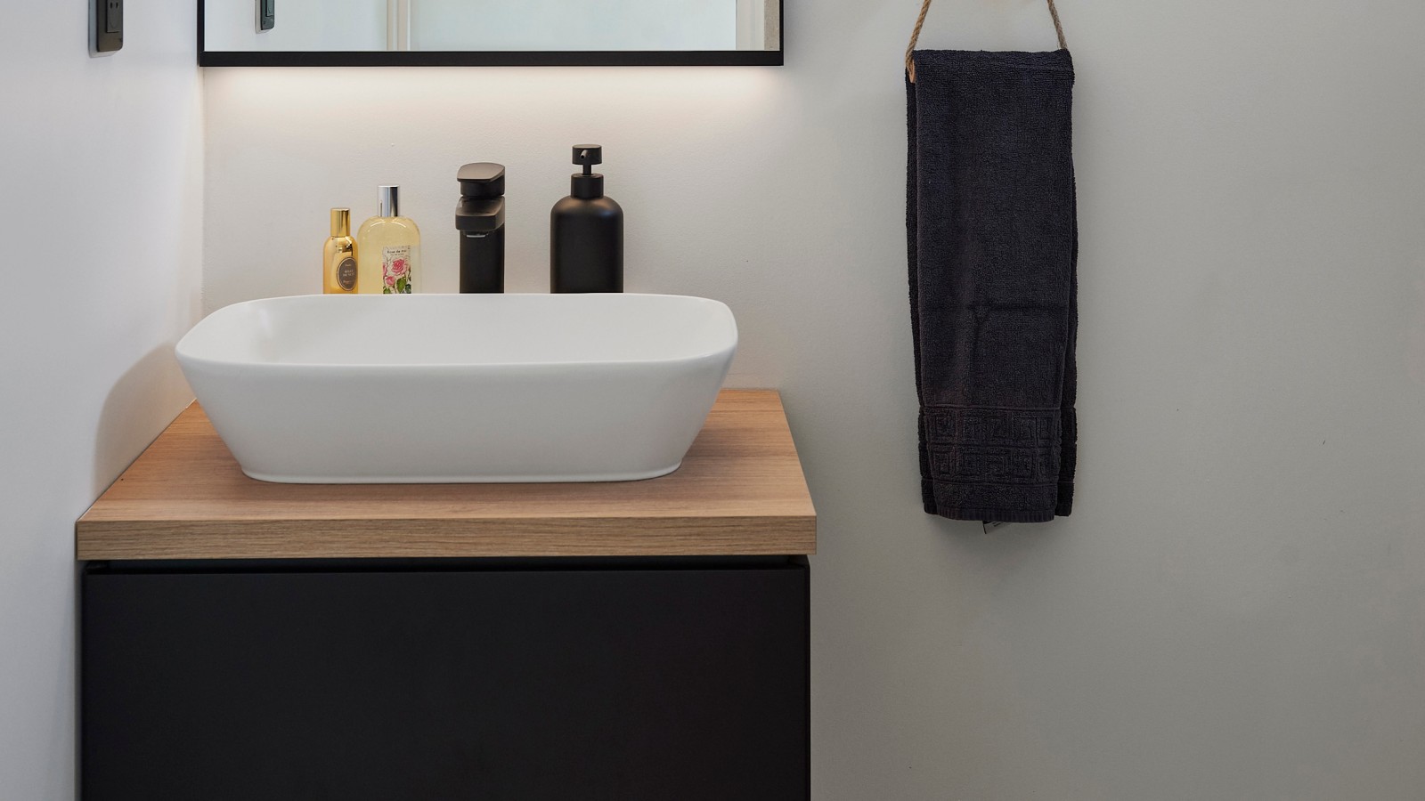 Waschplatz im Gästebad mit Geberit ONE Aufsatzwaschtisch und Unterschrank kombiniert mit Option Plus Square Lichtspiegel.