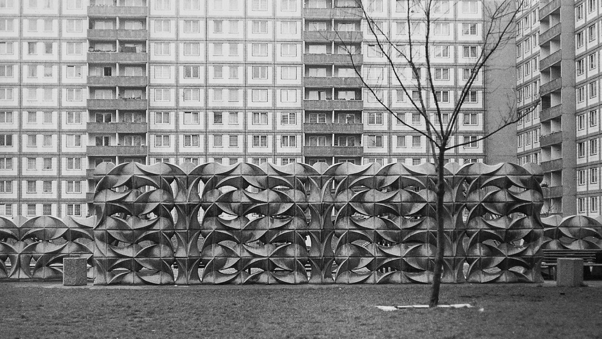 Organisch-geometrische Mauer aus Betonformsteinen im Kontrast zum Plattenbau