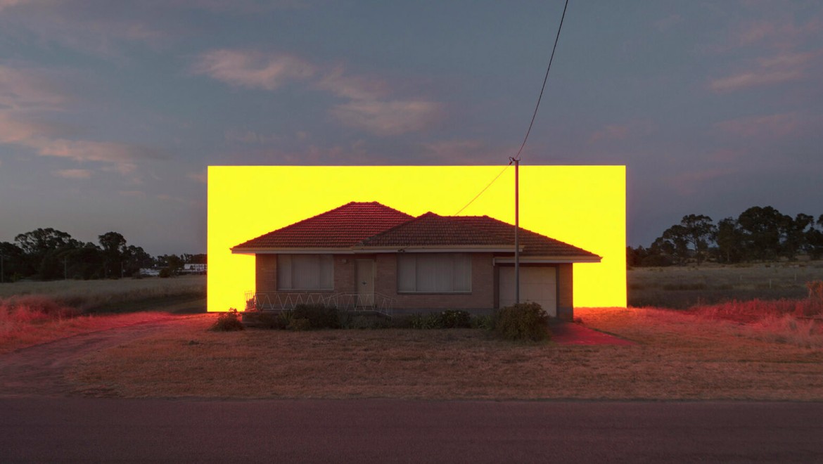 Kunstwerk von Ian Strange - Lichtinstallation in gelb hinter Haus