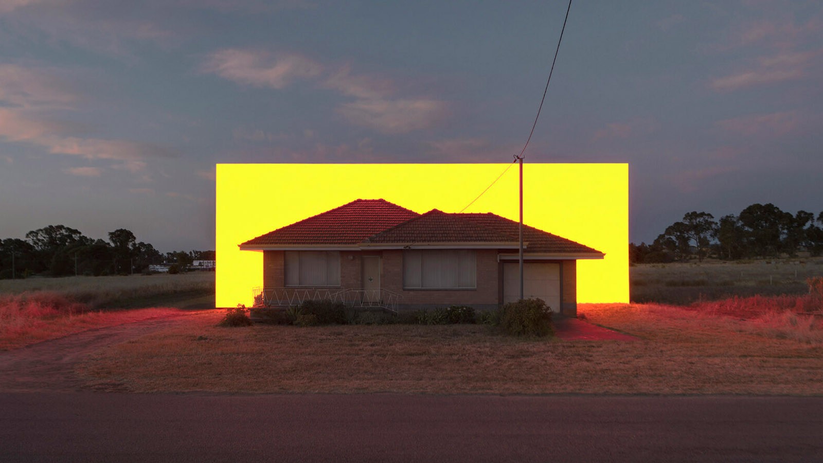 Kunstwerk von Ian Strange - Lichtinstallation in gelb hinter Haus