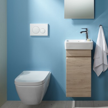 An einer hellblauen Wand ist ein wandhängendes Renova Plan WC und ein Waschplatz angebracht.