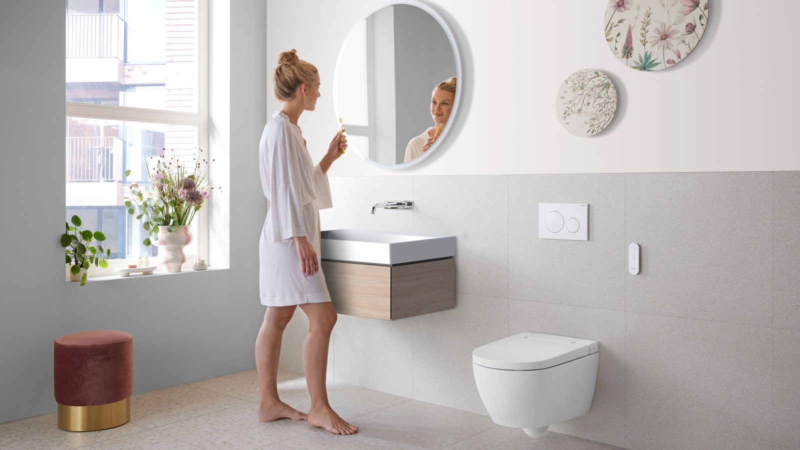 Frau in Badezimmer mit Geberit AquaClean Alba, einer preiswerten Toilette mit Waschfunktion Frau in Badezimmer mit Geberit AquaClean Alba, einer preiswerten Toilette mit Waschfunktion