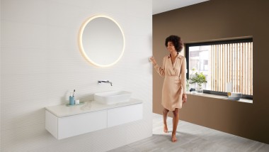 Frau in Badezimmer im trendigen Braunton mit Mix & Match-Waschplatz-Kombination Frau in Badezimmer im trendigen Braunton mit Mix & Match-Waschplatz-Kombination