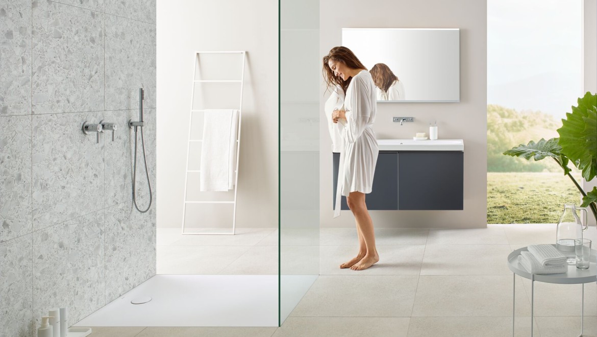 Frau steht in einem Badezimmer mit einer Walk-in-Dusche Frau steht in einem Badezimmer mit einer Walk-in-Dusche