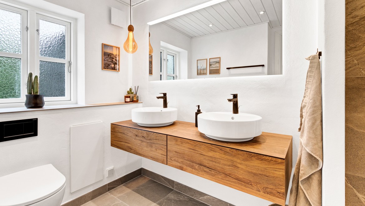 Renoviertes Bad des dänischen Ferienhauses mit einem Waschplatz der Serie Geberit VariForm und einem großen Spiegel mit integriertem Licht der Badserie Geberit Xeno².
