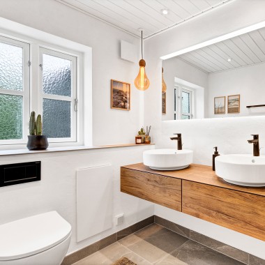 Helles, renoviertes Bad mit zwei runden Waschbecken, einem großen Spiegel und Badmöbeln aus Holz (© @triner2 und @strandparken3)