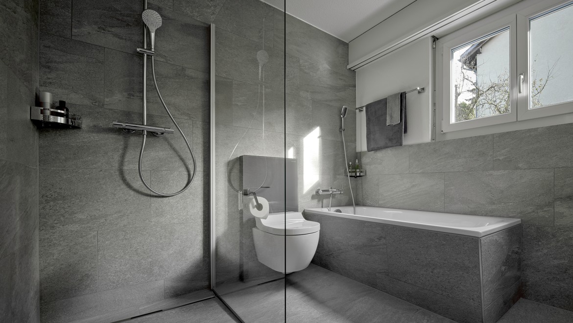 Bodenebene Dusche mit der Duschrinne Geberit CleanLine und einer Trennwand aus Glas.
