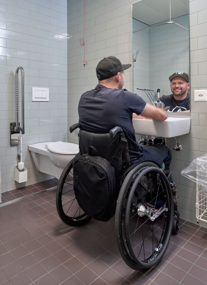 Peter Roos im Rollstuhl am Waschplatz in einem hindernisfreien Bad (© Ben Huggler)