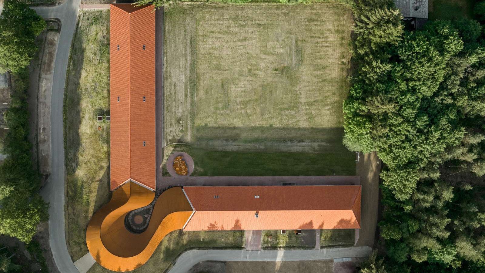 Der Blick von oben zeigt den runden Neubau, der die beiden historischen Gebäude mit den Ziegeldächern miteinander verbindet (© R. Hjortshoj) Der Blick von oben zeigt den runden Neubau, der die beiden historischen Gebäude mit den Ziegeldächern miteinander verbindet (© R. Hjortshoj)