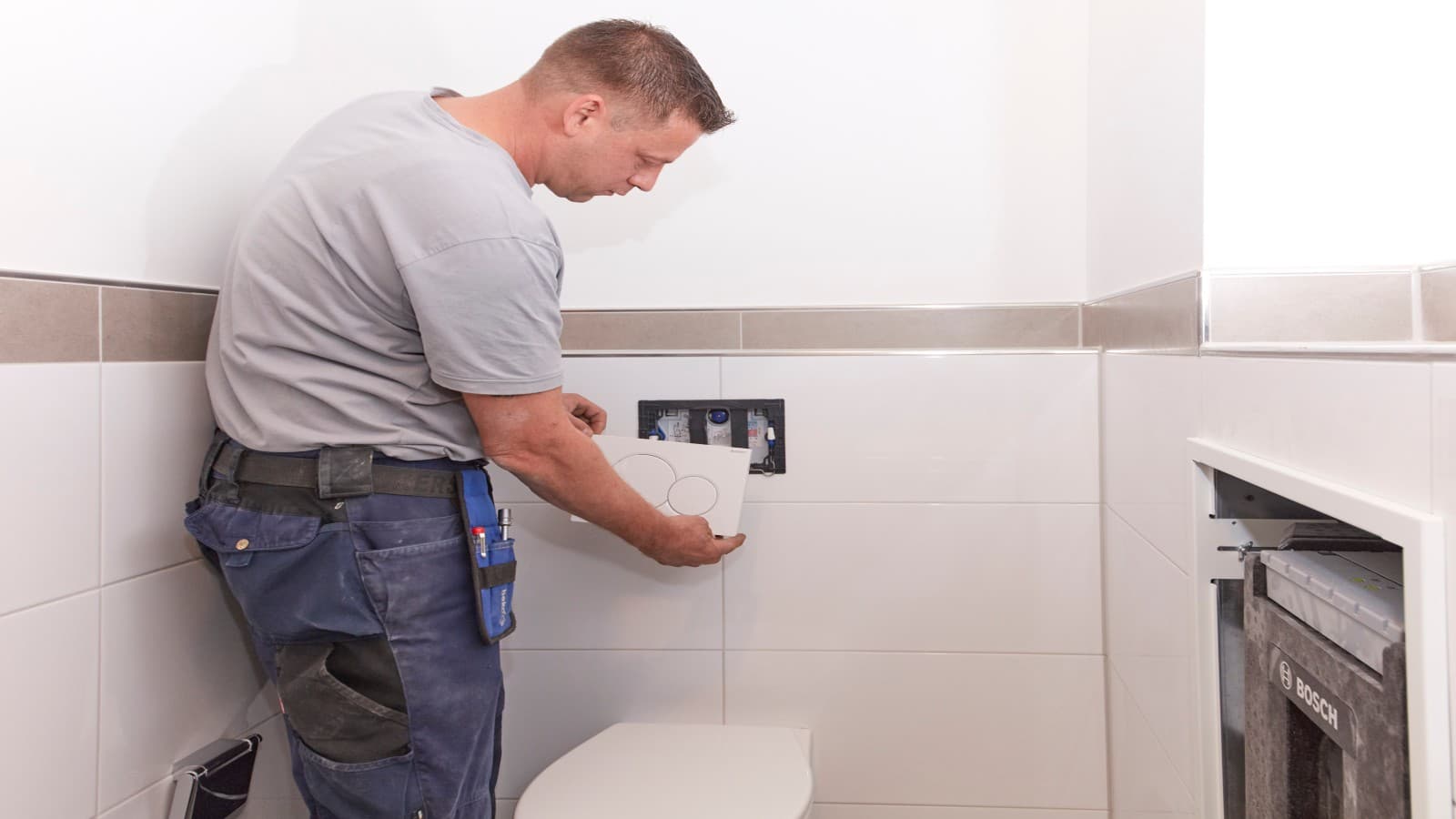 Installateur bringt WC-Betätigungsplatte an, Foto: Bosch Installateur bringt WC-Betätigungsplatte an, Foto: Bosch